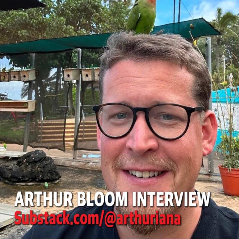 Selfie of a man with round glasses outdoors, a green parrot perched on his head, with overlaid interview promo text: 'ARTHUR BLOOM INTERVIEW' and 'Substack.com/@arthuriana'.